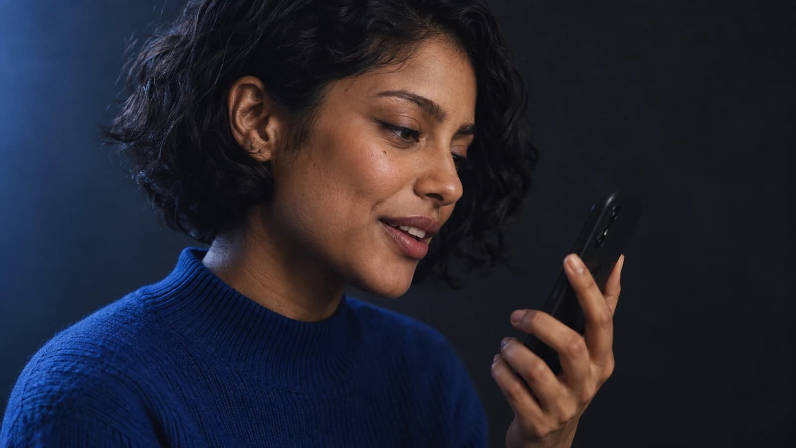 An editorial photograph of a fictional adult woman speaking into her phone.